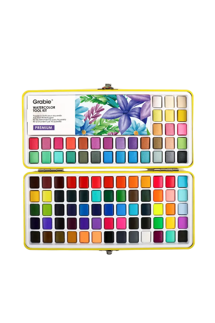 Grable Watercolor Tool Kit in a yellow metal case, shown open to display 100 color pans and a floral watercolor design printed on the inside cover.