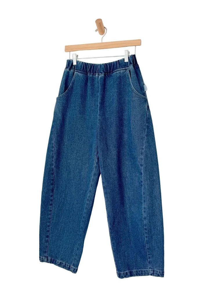Blue jeans hanging on a wooden hanger against a white background