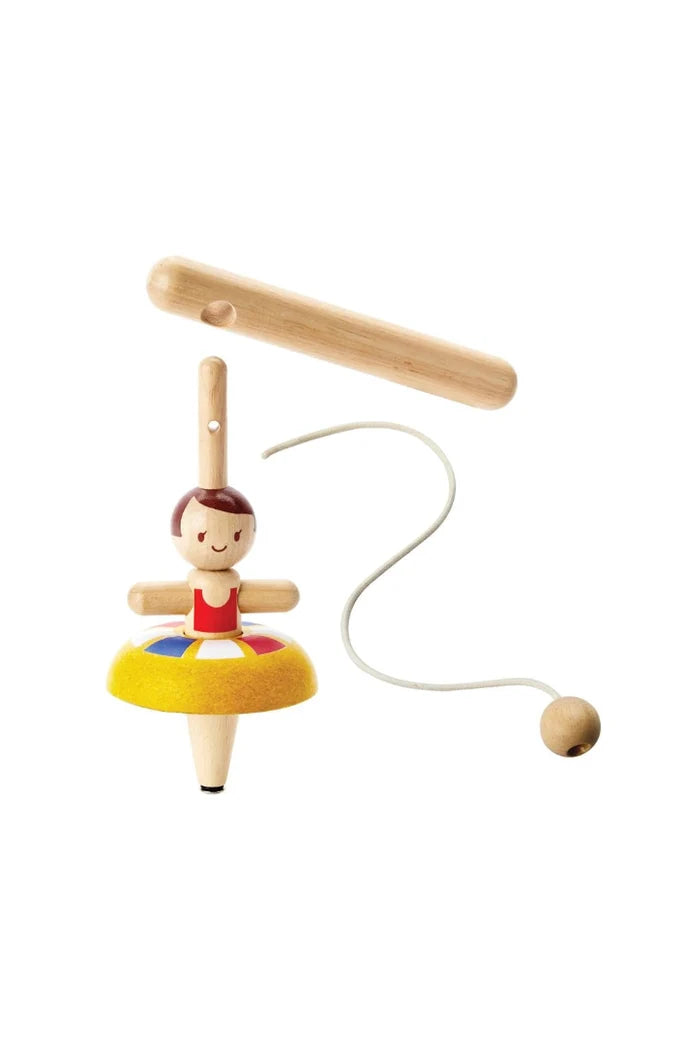A wooden dancer toy with a spinning top handle, a wooden stick, and a white string ending in a wooden ball, featuring a small painted ballerina figure with a yellow skirt.
