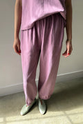 Person wearing a pink outfit with matching pants and top against a neutral background