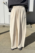 Person wearing beige wide-leg pants and a dark top outdoors.