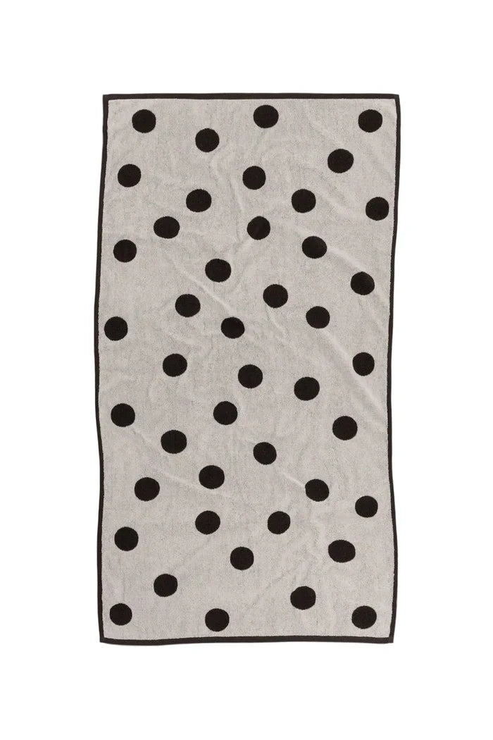 White bath towel with black polka dots on white background