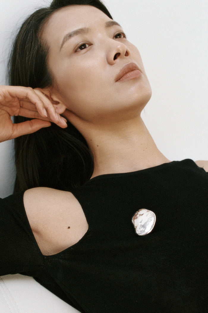 Woman wearing a black top with a decorative brooch on a white background