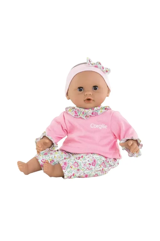 A baby doll wearing a pink long-sleeve top with a floral collar, matching floral pants, and a pink headband with a bow, shown against a plain white background.