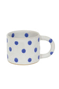 White mug with blue polka dots on a white background