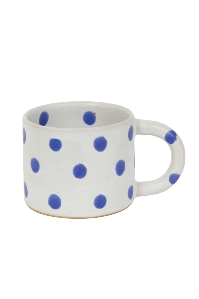 White mug with blue polka dots on a white background