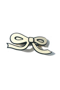 A white, bow shaped acetate hair barrette with a black border