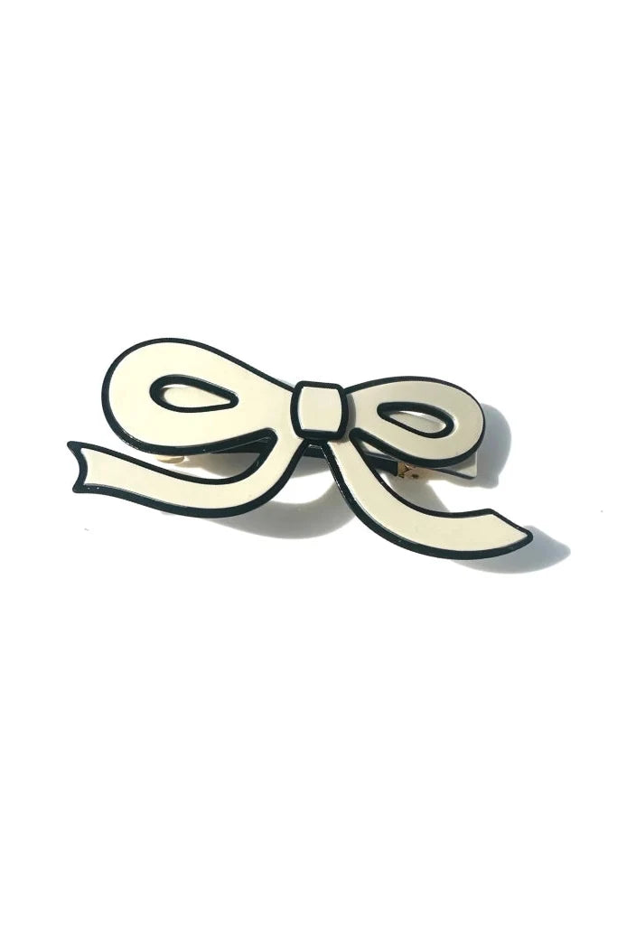 A white, bow shaped acetate hair barrette with a black border