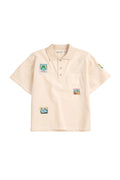 Beige polo shirt with colorful patches on a white background