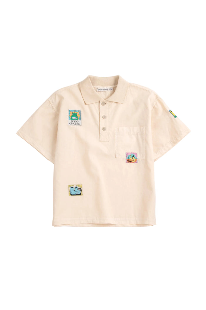 Beige polo shirt with colorful patches on a white background