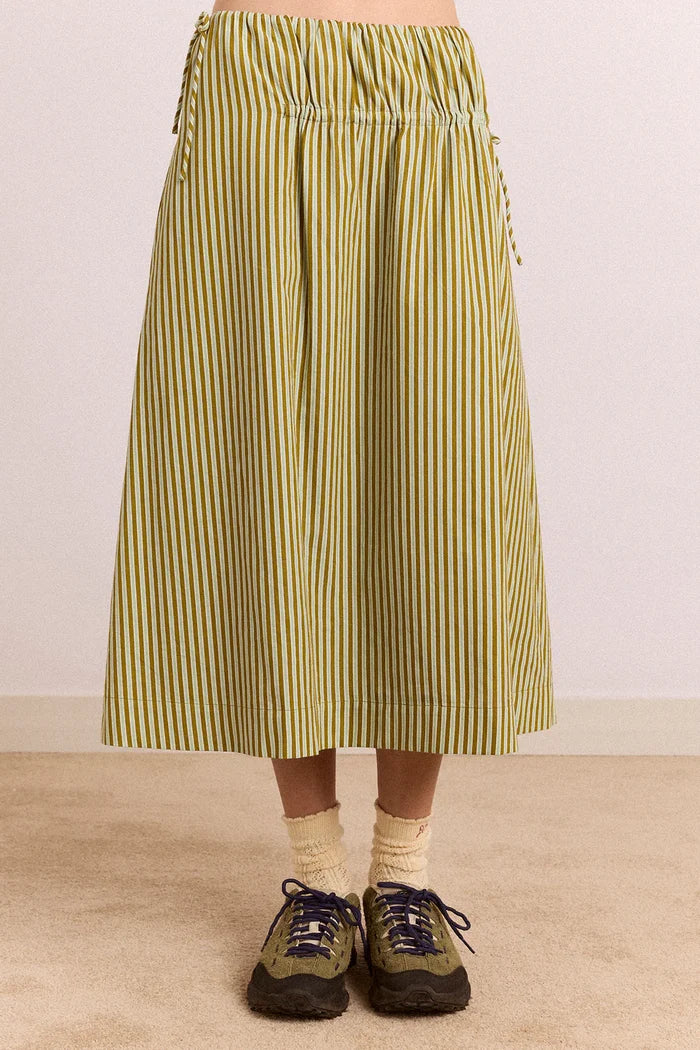 Person wearing a green and white striped skirt on a plain background