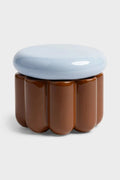 Jar with scalloped sides on white background. The body of the jar is brown and the lid is light blue.