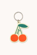 Cherry-shaped keychain with a green stem on a white background
