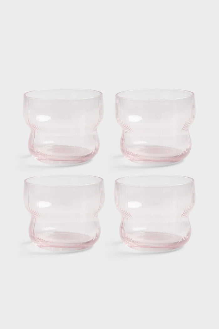 Four pink glass tumblers on a white background