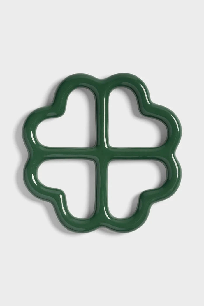Green ceramic trivet shaped like a clover on a white background.