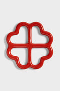 Red ceramic trivet shaped like a clover on a white background