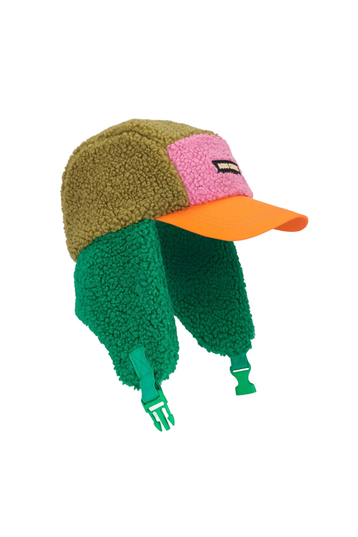 A fleece winter cap with ear flaps, featuring a color-blocked design in olive green, pink, and green, with an orange brim and green chin straps, shown on a light gray background.