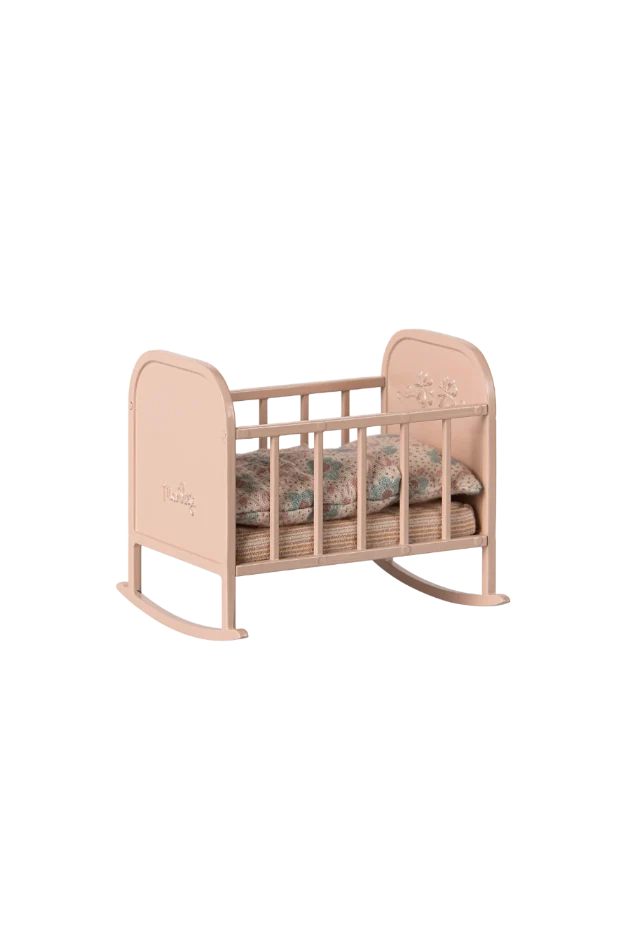 Pink baby crib with floral bedding on a white background