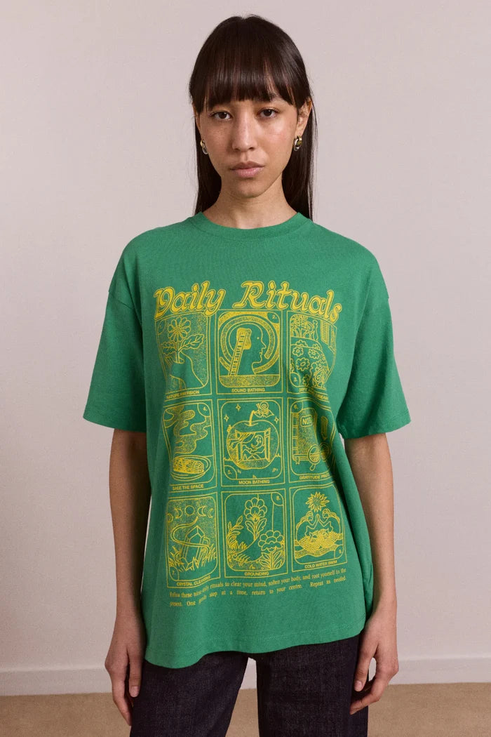 Person wearing a green t-shirt with yellow text and graphics against a plain background