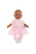 A baby doll with a bald head and dark skin wearing a light pink outfit with a tutu skirt, white bow, and white shoes, photographed against a plain white background.