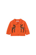 An orange knit cardigan sweater featuring two embroidered deer motifs on the front, displayed against a solid off-white background.