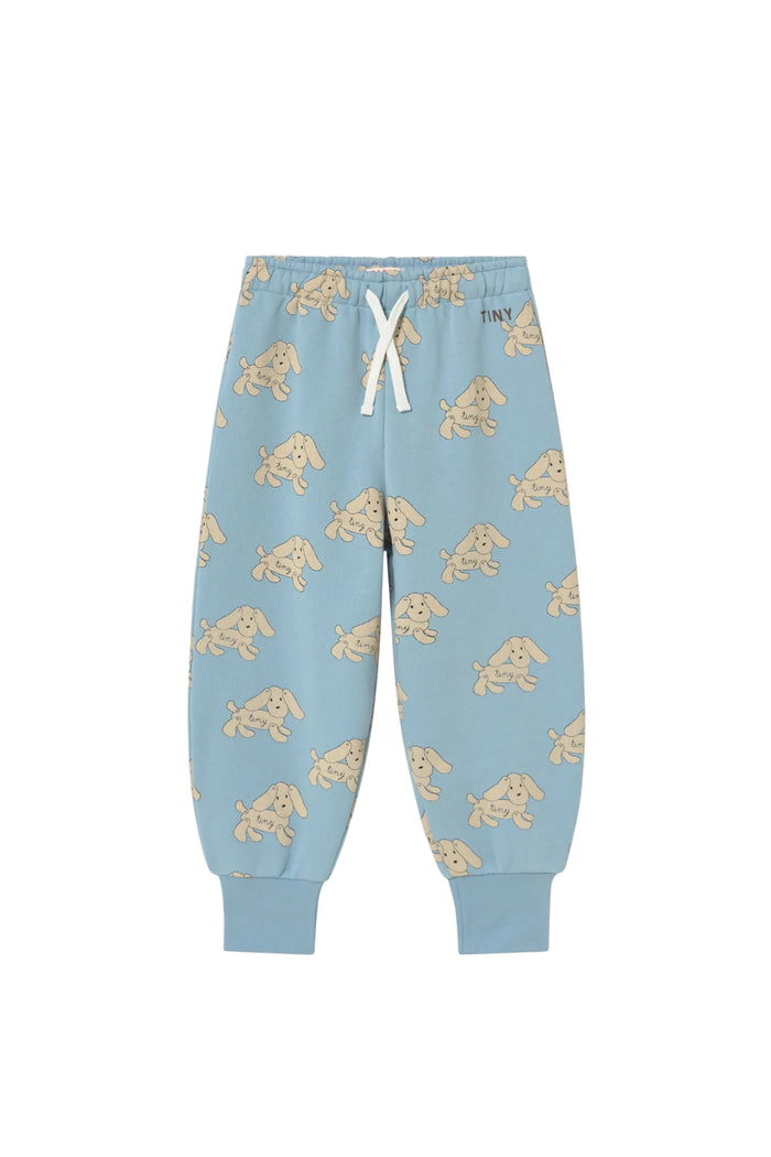Light blue jogger pants with an all-over puppy print, featuring a white drawstring waist and ribbed ankle cuffs, shown flat on a light cream background.
