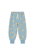 Light blue jogger pants with an all-over puppy print, featuring a white drawstring waist and ribbed ankle cuffs, shown flat on a light cream background.