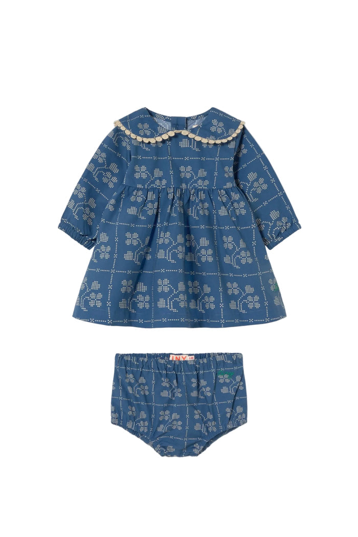 A baby girl's two-piece outfit set consisting of a long-sleeve smocked blouse and matching bloomers, both in a blue denim-like fabric with a white floral print and a cream beaded collar, shown on a plain off-white background.