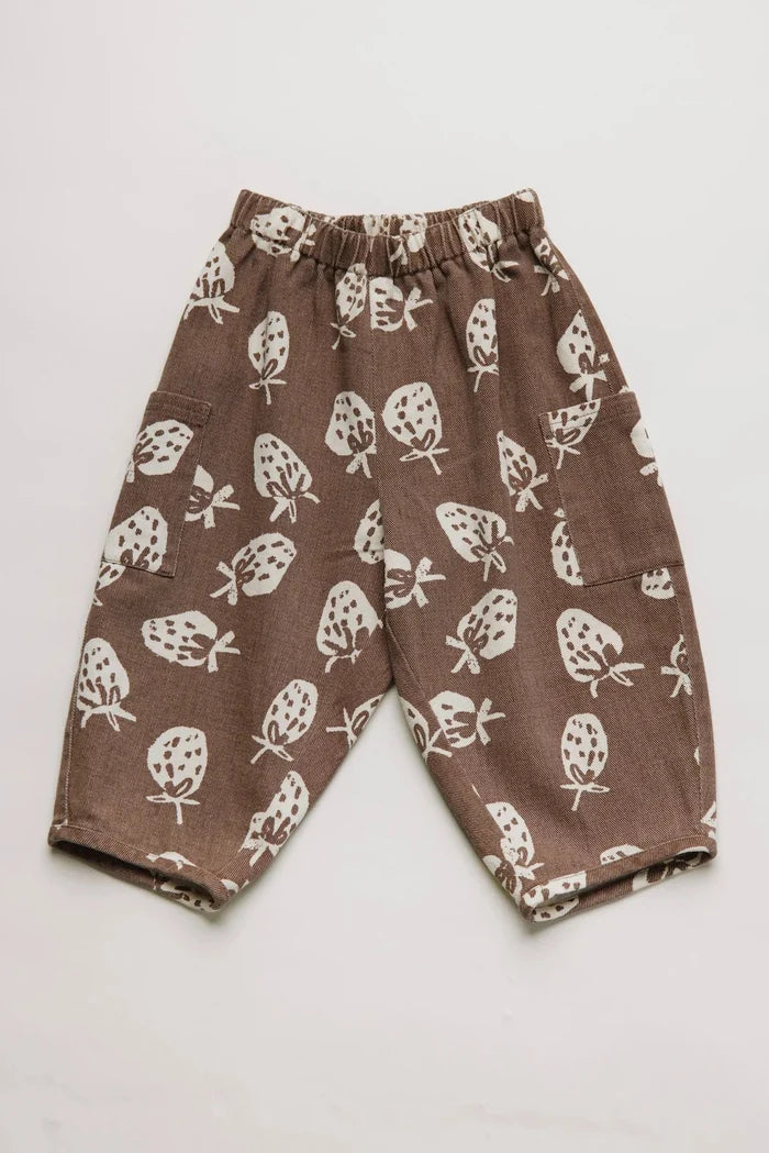 Brown pants with white strawberry pattern on a light gray background