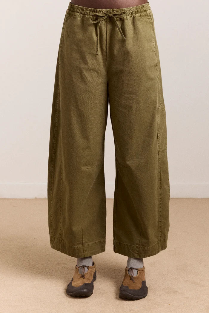 Green wide-leg pants worn by a person on a beige floor with a white wall background