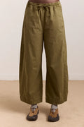 Green wide-leg pants worn by a person on a beige floor with a white wall background