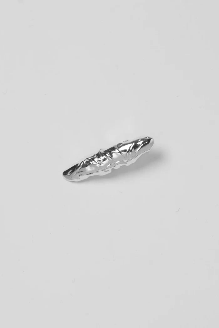 Silver hair clip with a textured design on a light gray background