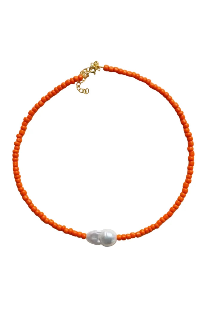 Orange beaded necklace with a pearl pendant on a light gray background