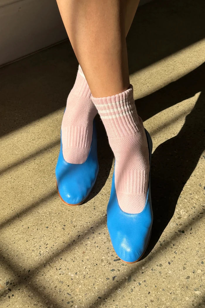 Blue shoes with pink socks on a concrete surface