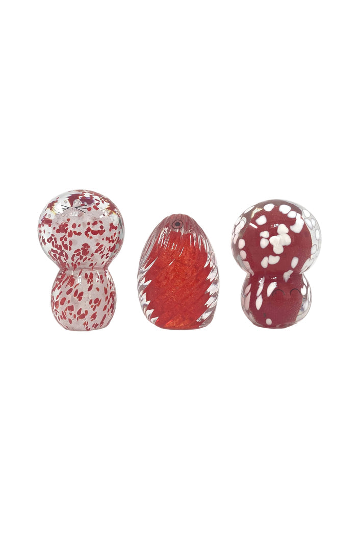 Three small decorative glass objects with red and white speckled patterns, displayed on a clean white background.