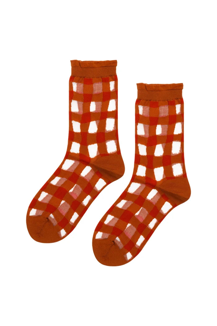 A pair of orange crew socks with a red and sheer gingham plaid pattern, displayed against a plain white background.