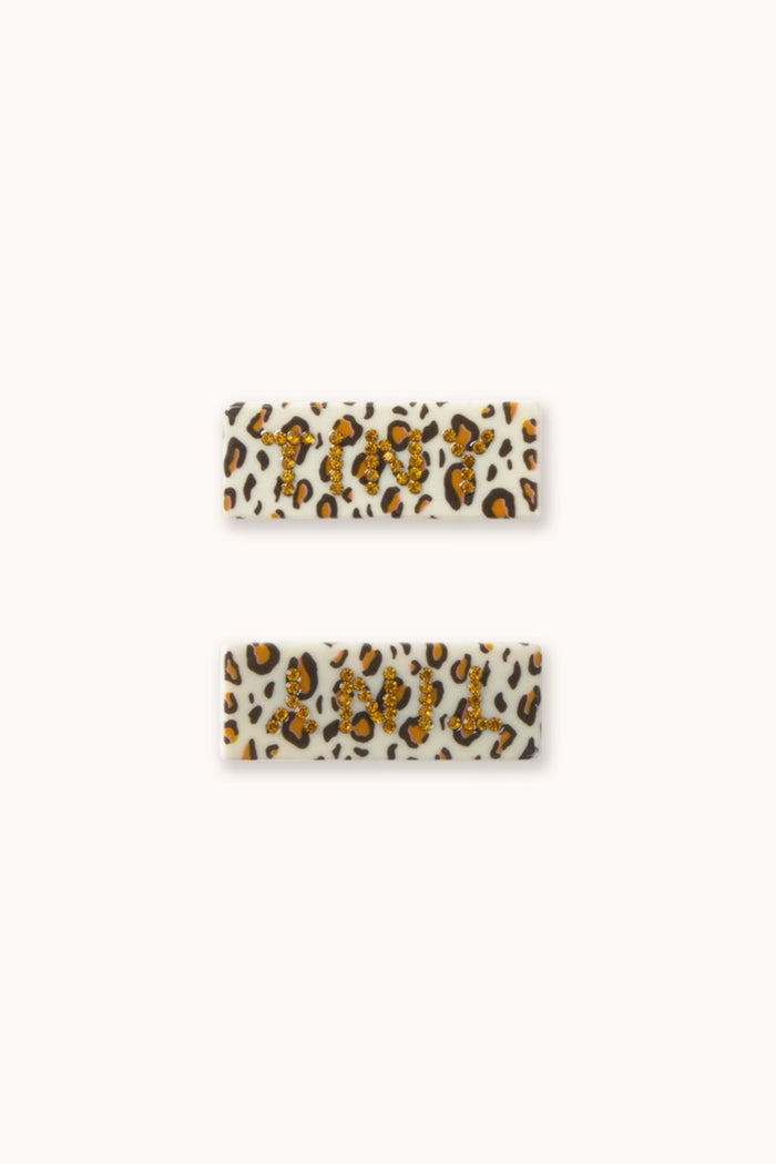 Plastic hair clips with animal print and 'TINY' logo on white background