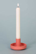 Candle in a pink holder on a gray background
