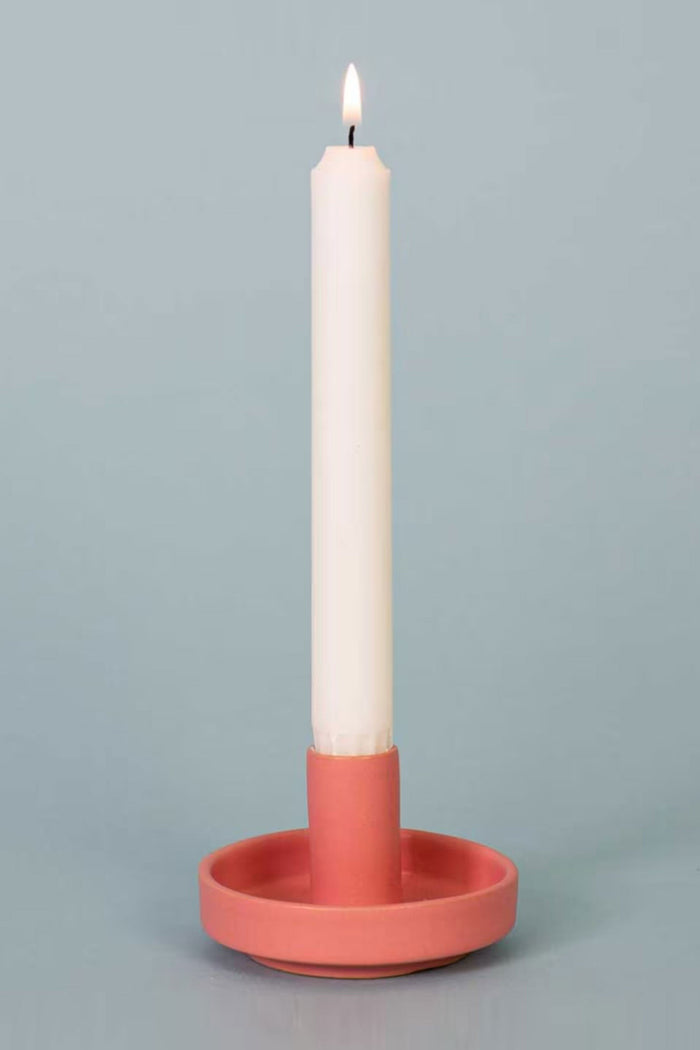 Candle in a pink holder on a gray background