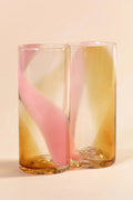 Two tall glass cups with pink and orange streaks on pink background