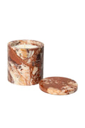 A marble candle jar with a matching round lid placed in front, set against a clean light gray studio background. The candle wax is visible at the top, and the marble features a mix of warm brown, terracotta, cream, and beige veining.