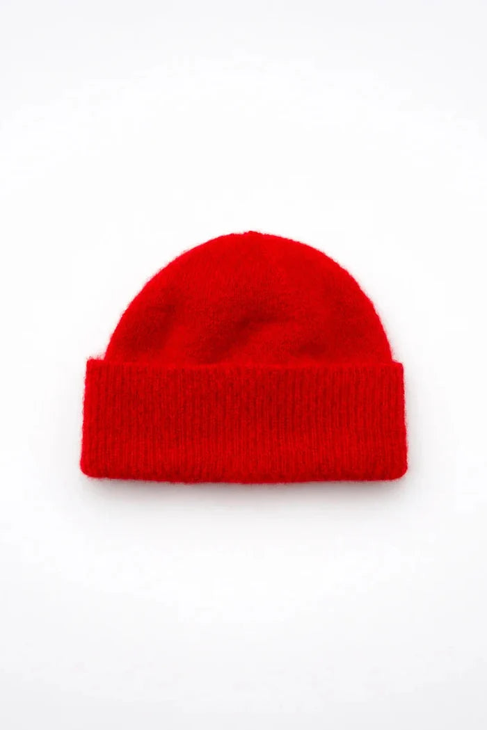 A bright red knit beanie hat, photographed from directly above on a clean white background.