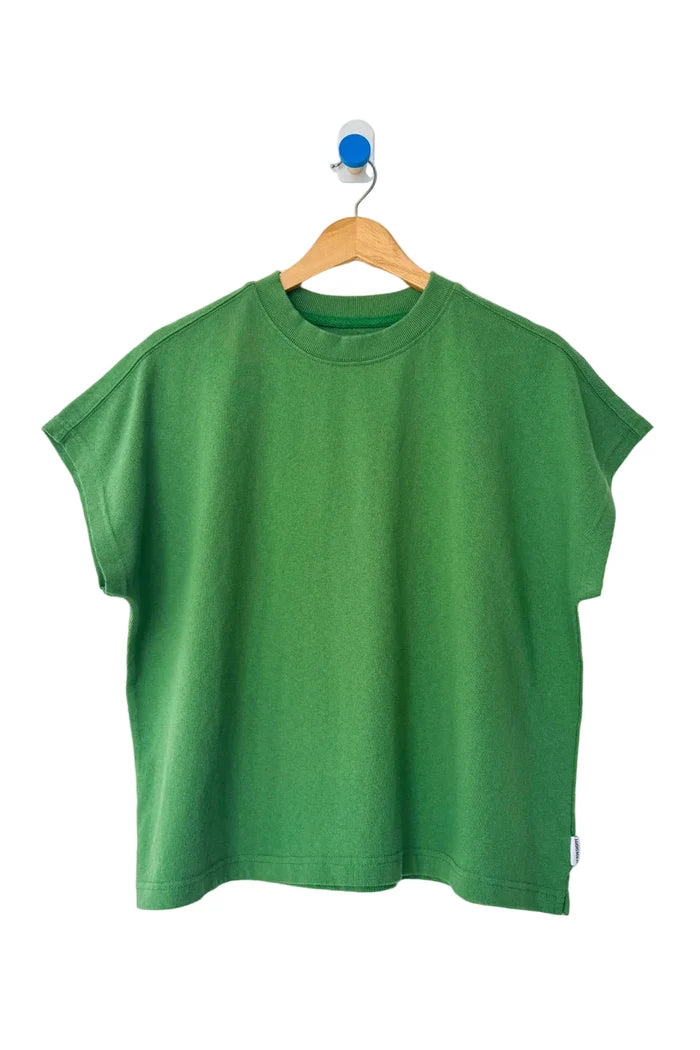 A green short-sleeve crewneck t-shirt hanging on a wooden hanger against a plain white wall.