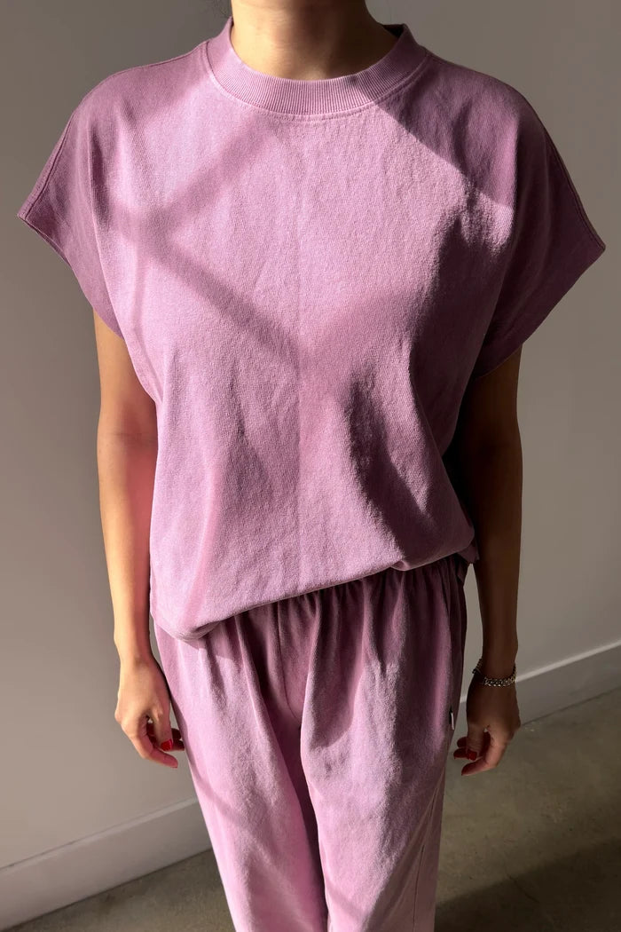 Person wearing a pink outfit with a dark stain on a plain background