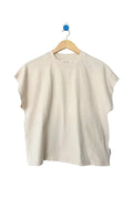 A cream-colored short-sleeve crewneck t-shirt hanging on a wooden hanger against a light gray background.