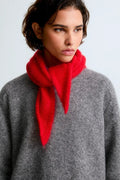 Person wearing a bright red scarf and gray sweater against a light background