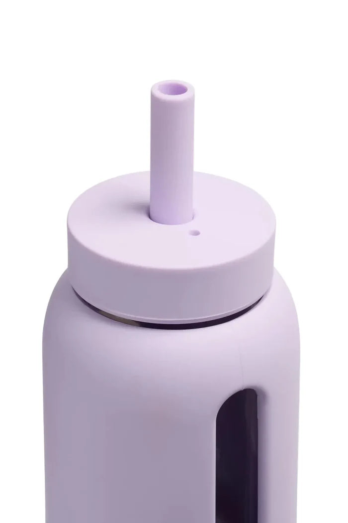 Light purple silicone and glass water bottle with straw on white background