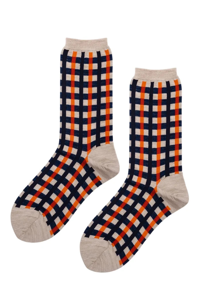 A pair of crew socks with a navy blue, orange, and beige plaid pattern, shown against a plain white background.