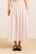 Person wearing a white skirt with red pattern on a beige background