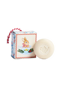 A round cream-colored soap bar with a ribbed texture and an embossed teapot, shown next to its decorative illustrated gift box featuring a bunny in a teacup.
